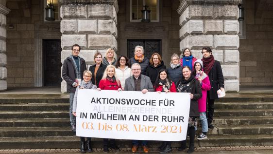 Akteure halten den Banner der Aktionswoche für Alleinerziehende hoch