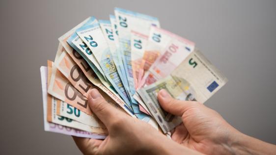 Zwei Hände halten Geldscheine in der Hand.