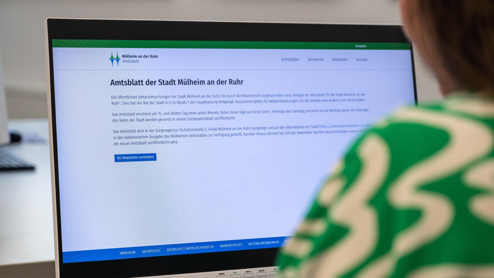 Person liest auf einem Bildschirm die Webseite des Amtsblatts der Stadt Mülheim an der Ruhr mit Informationen zu öffentlichen Bekanntmachungen und Newsletter-Anmeldung
