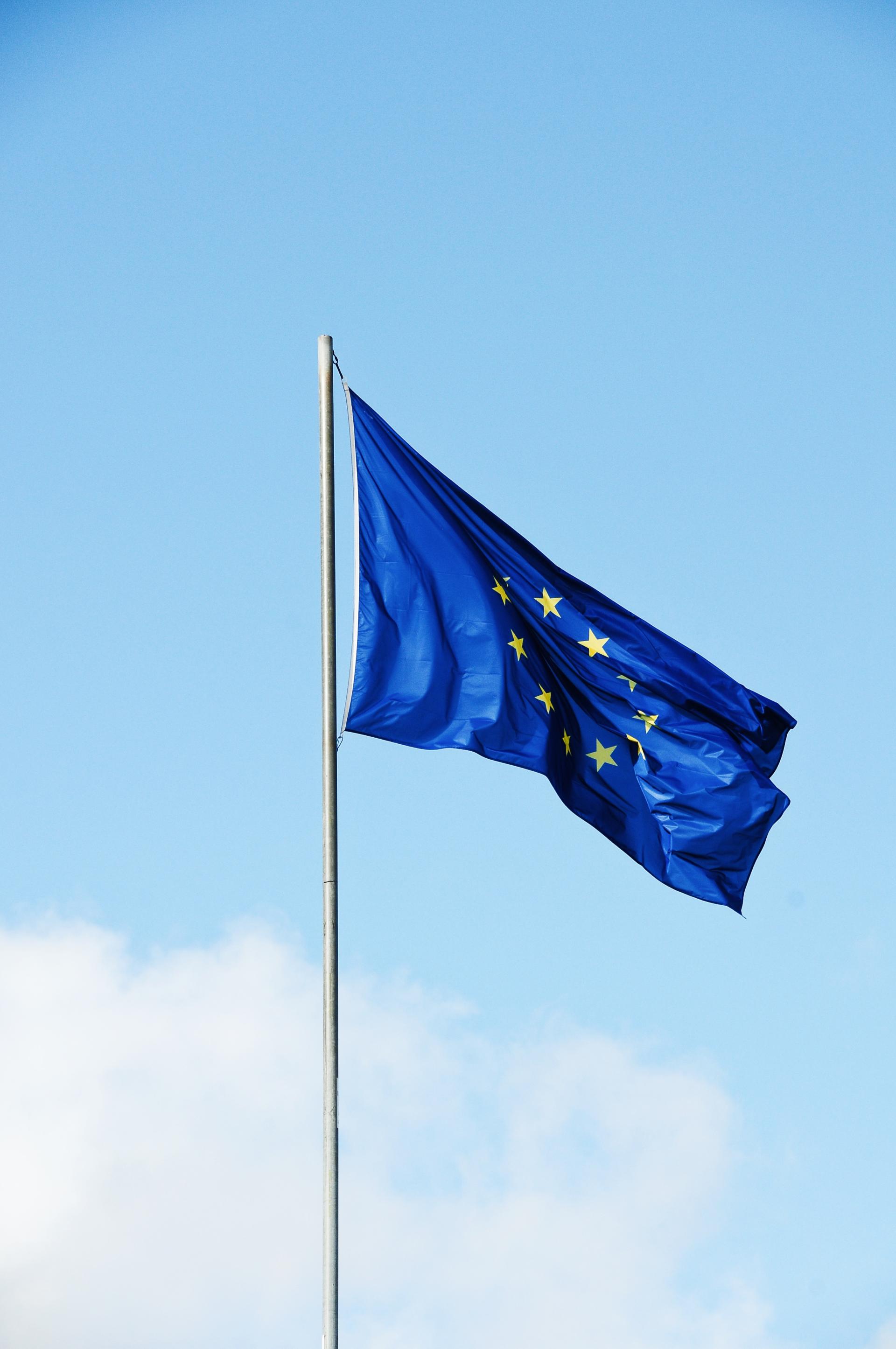 Die Europaflagge vor einem blauen Himmel wehend.