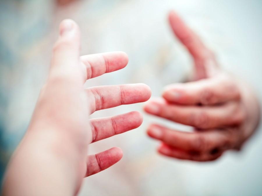 Eine Hand nähert sich einer anderen Hand um Hilfe anzubieten