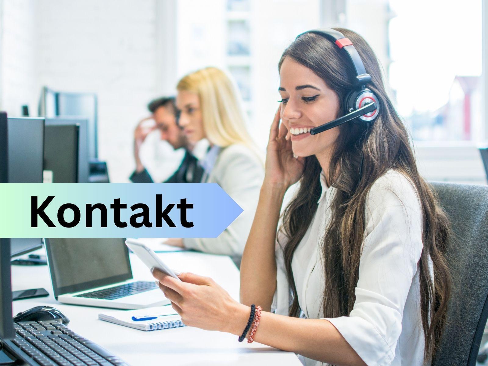 Eine Frau in einem Büro telefoniert. Im Hintergrund befinden sich eine Arbeitskollegin und ein Arbeitskollege.