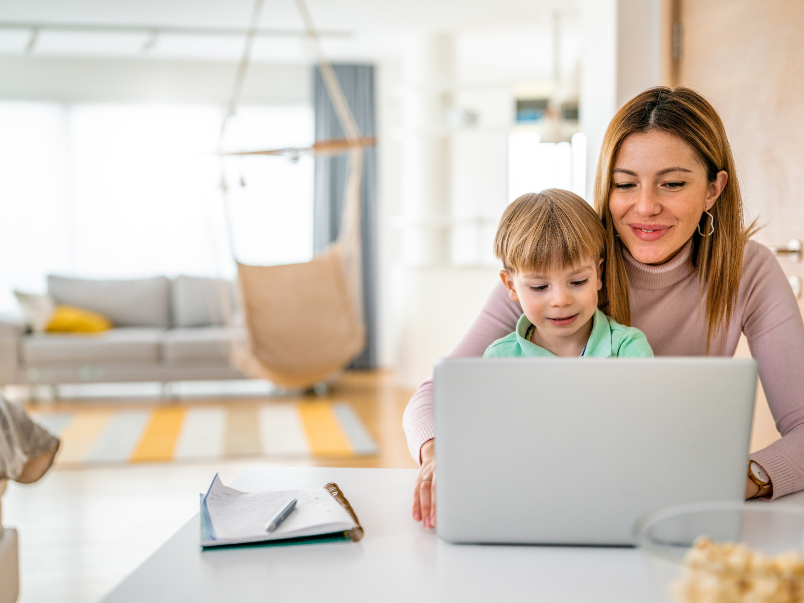 Mutter mit Sohn schaut auf den Laptop und lachen freundlich.