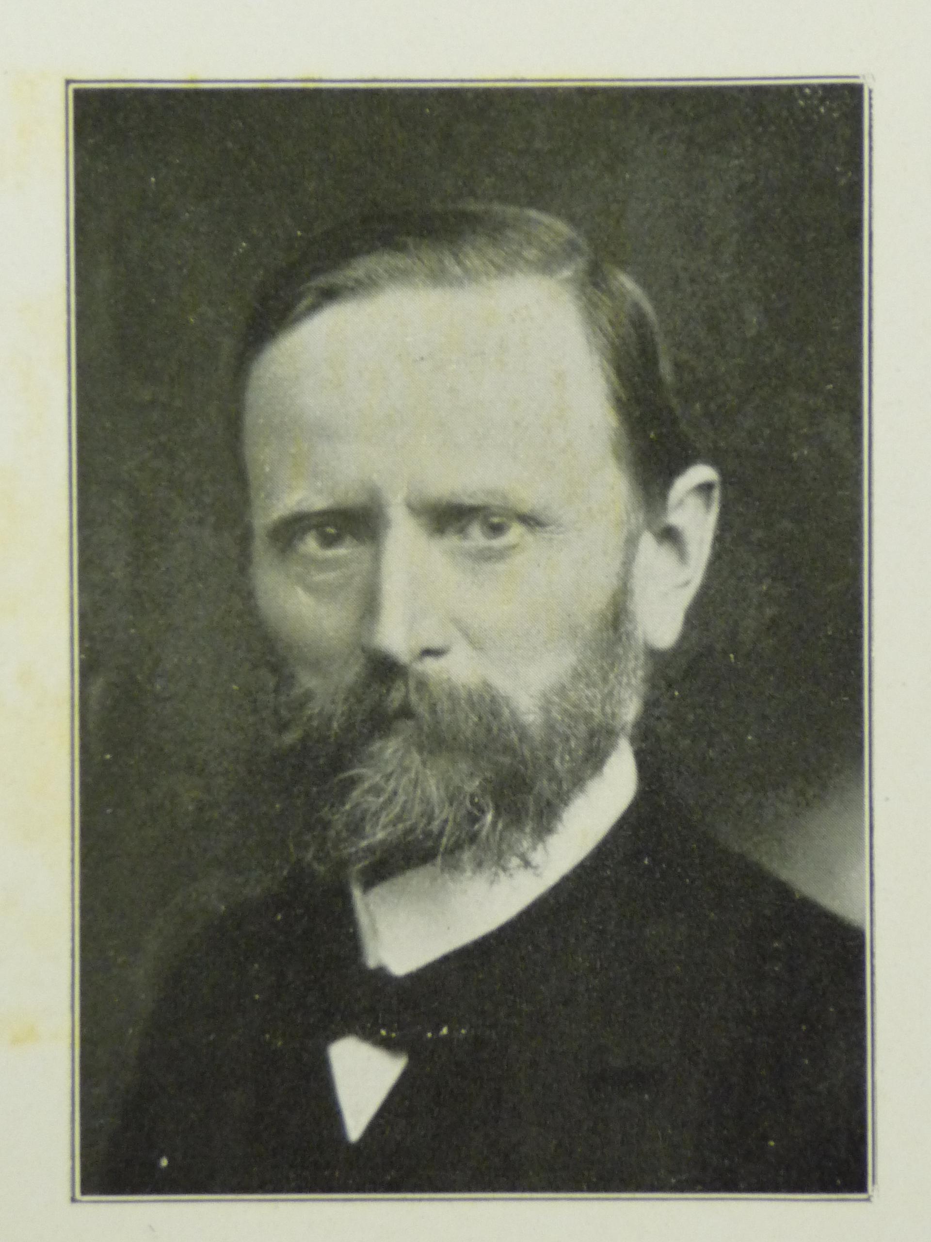 Das Bild ist ein Portraitfoto eines älteren Herren mit etwas längerem dunklen Vollbart.