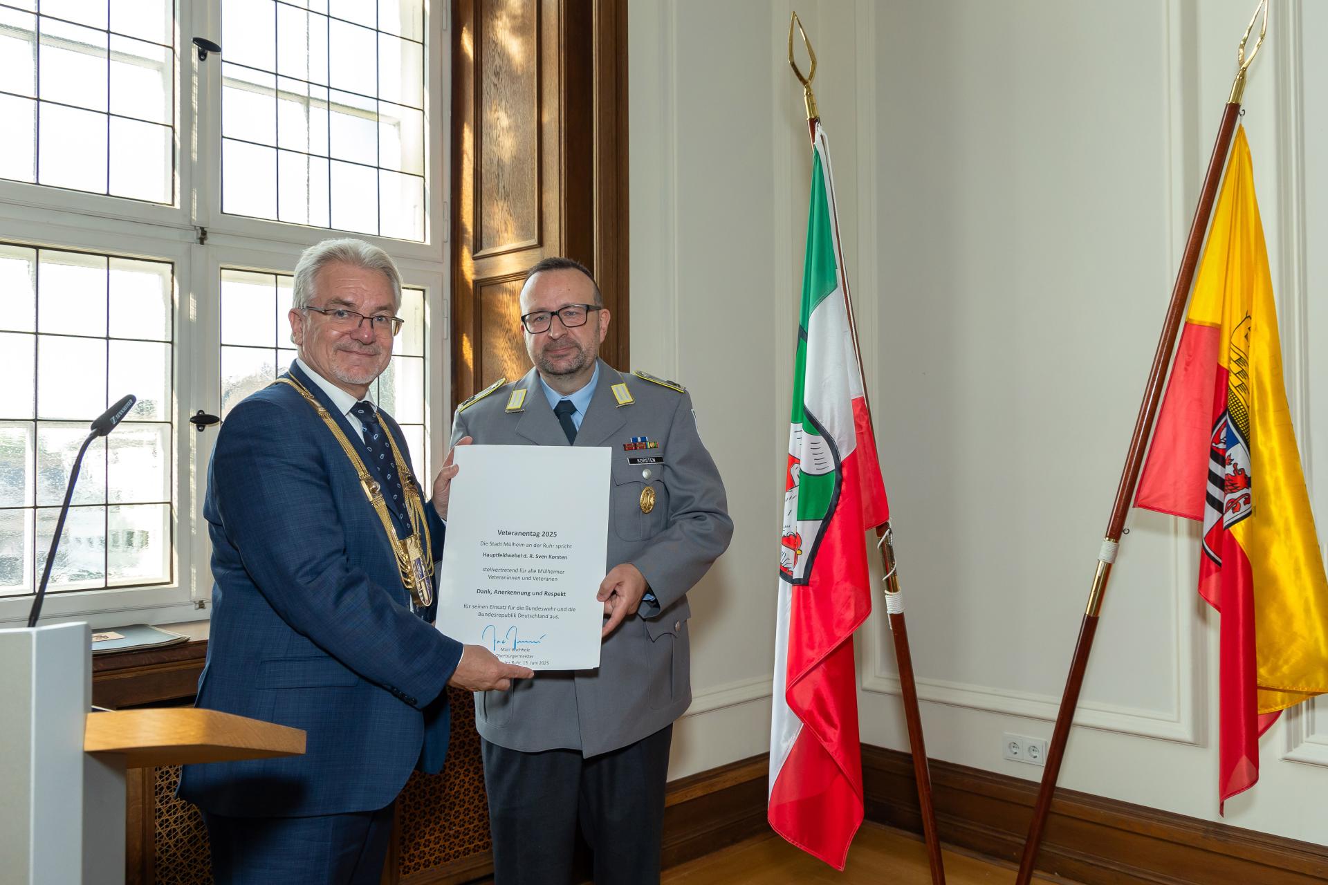 Oberbürgermeister Marc Buchholz überreicht Hauptfeldwebel d.R. Sven Korsten eine Urkunde als Würdigung für seinen Einsatz.
