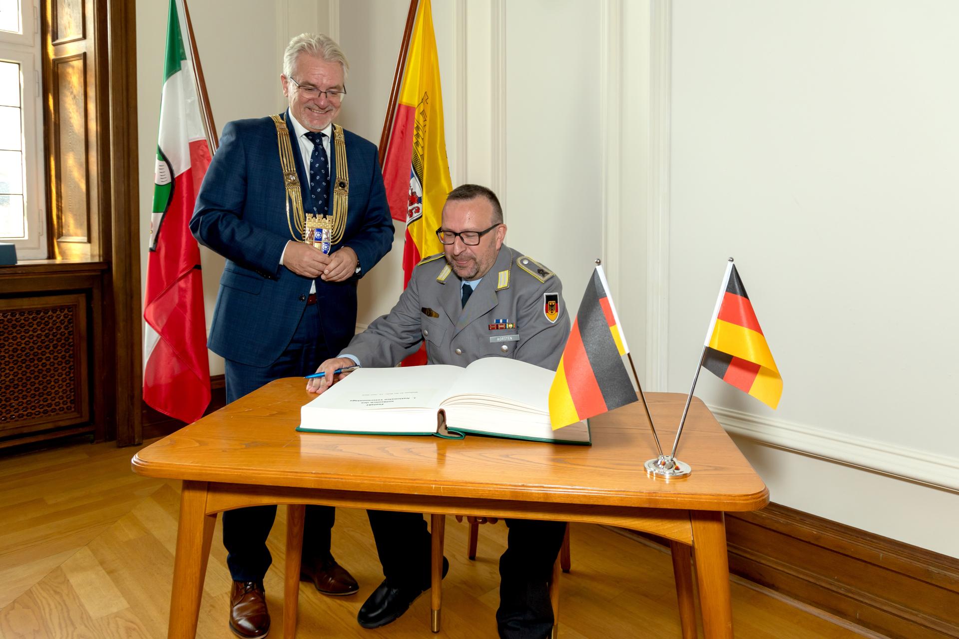 Hauptfeldwebel d.R. Sven Korsten trägt sich im Beisein von Oberbürgermeister Marc Buchholz ins Gästebuch der Stadt Mülheim an der Ruhr ein.