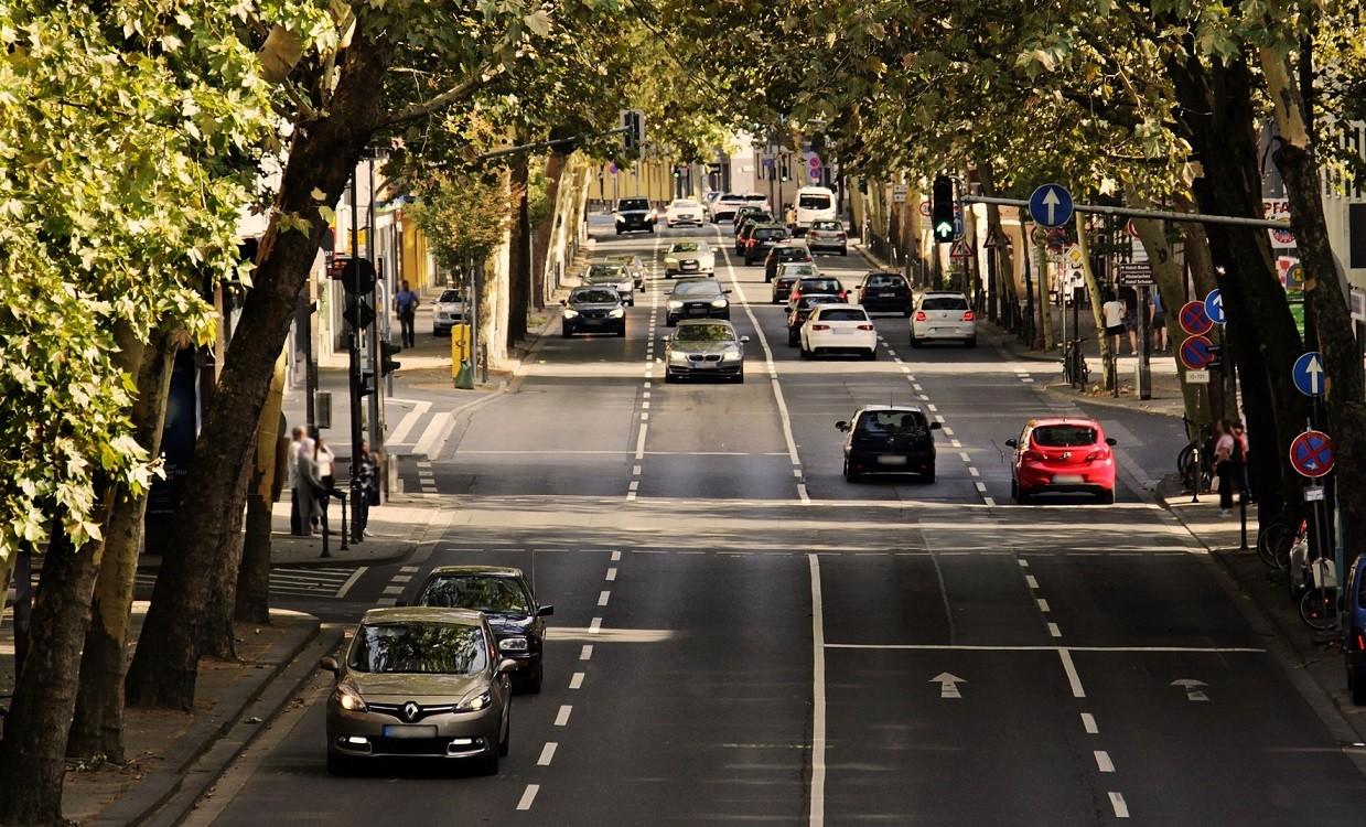 Straßenverkehr in einer Allee in Mitten einer Stadt.