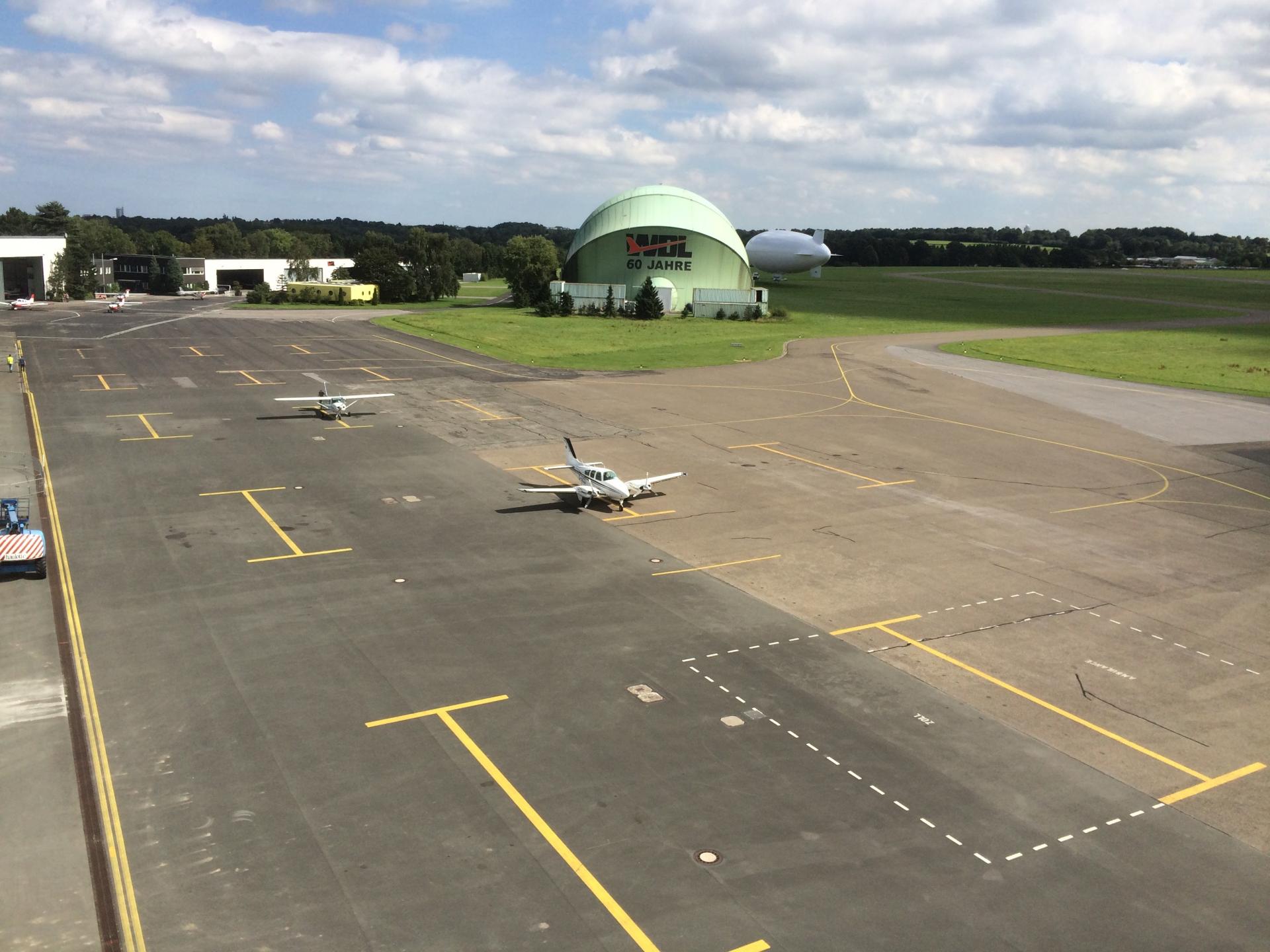 Eine Start- und Landebahn auf dem Flughafen Essen-Mülheim, im Hintergrund die ehemalige WDL-Luftschiffhalle
