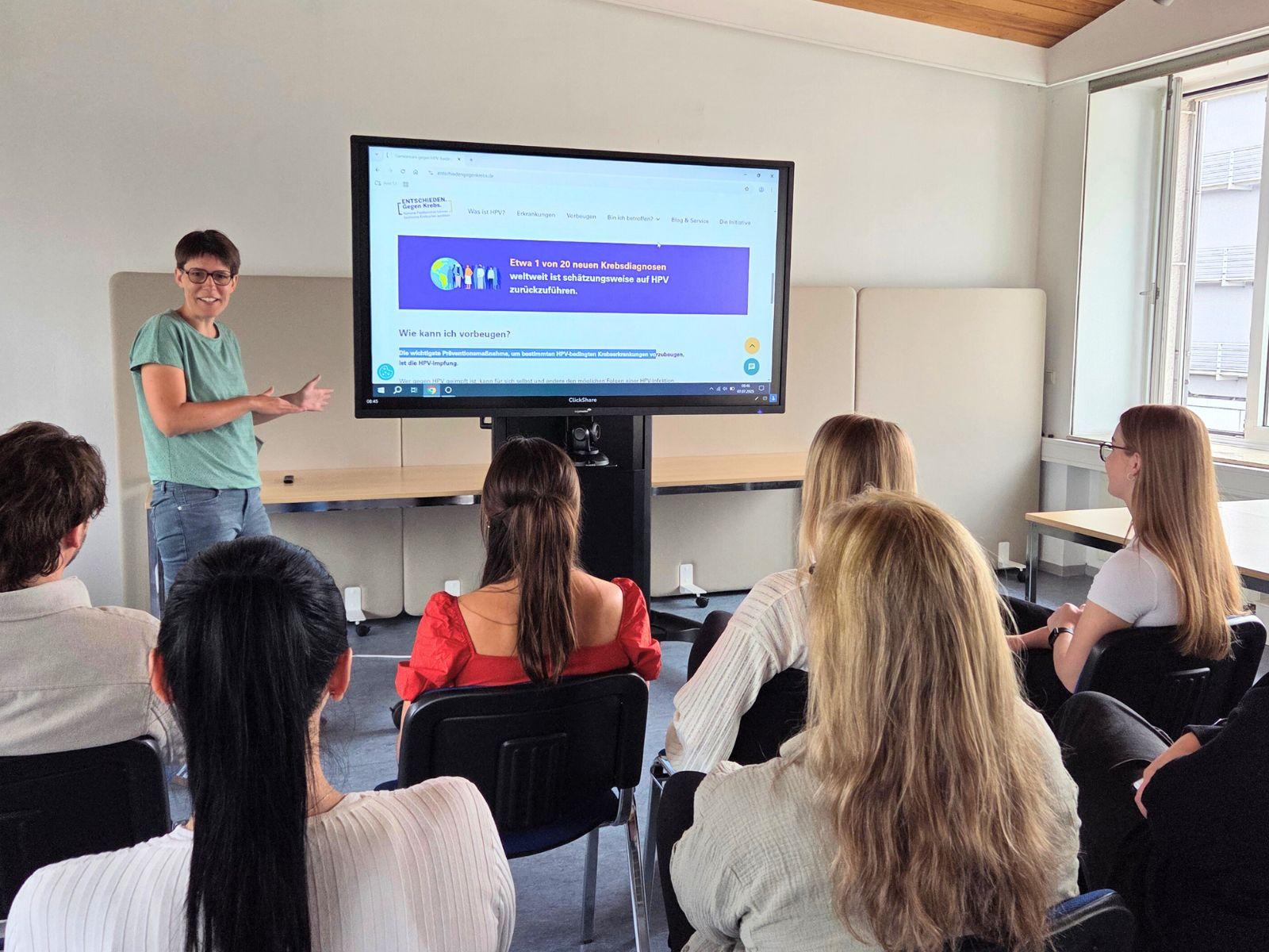 Dr. Susanne Härtig beim Vortrag über HPV. Besucher*innen hören aufmerksam zu.