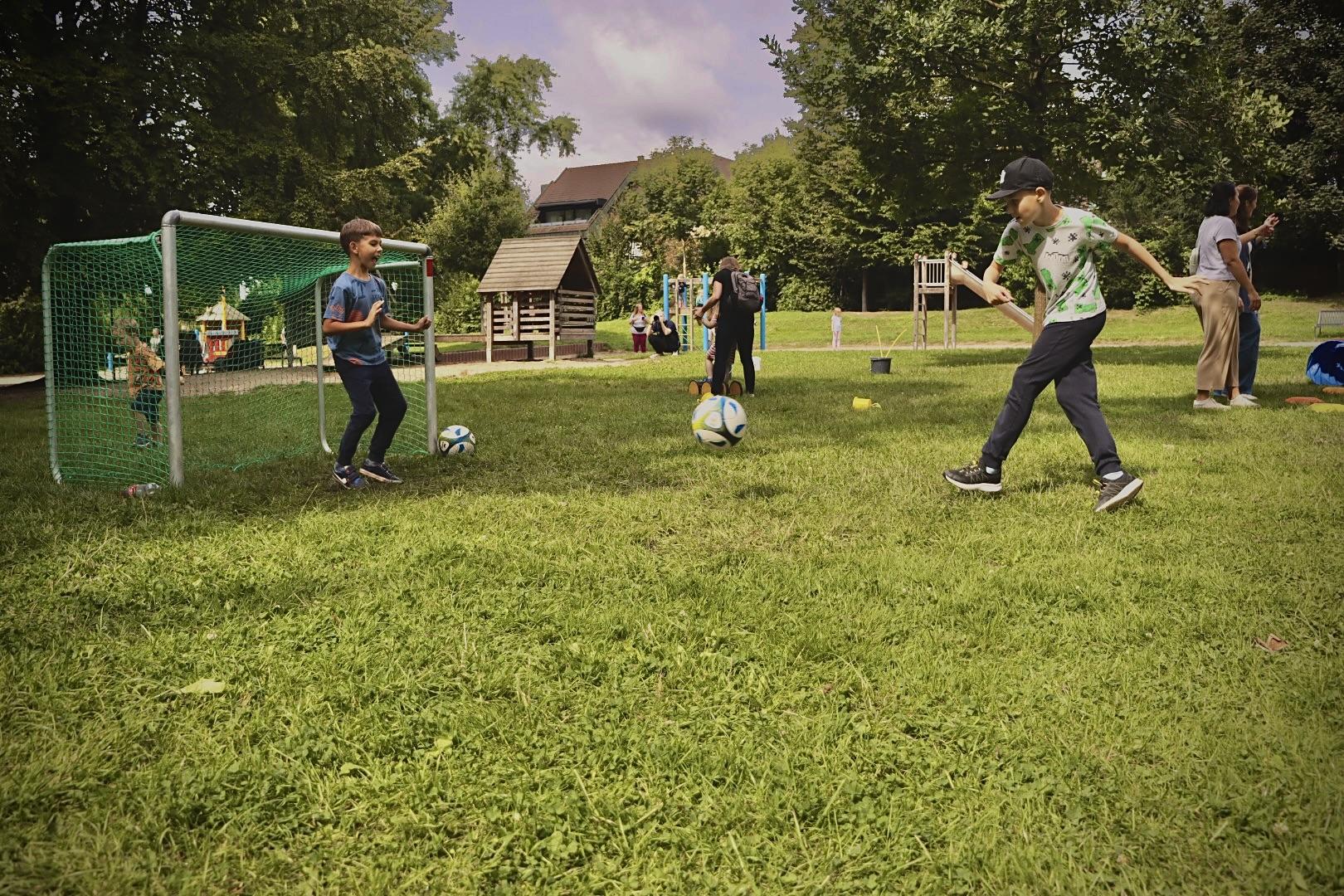 Drei Kinder spielen Fußball auf einer Wiese.