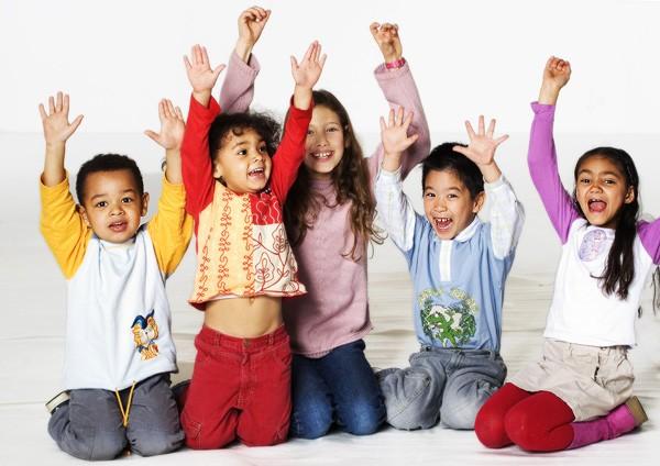 Kinder aus verschiedenen Herkunftsländern recken jubelnd ihre Arme nach oben