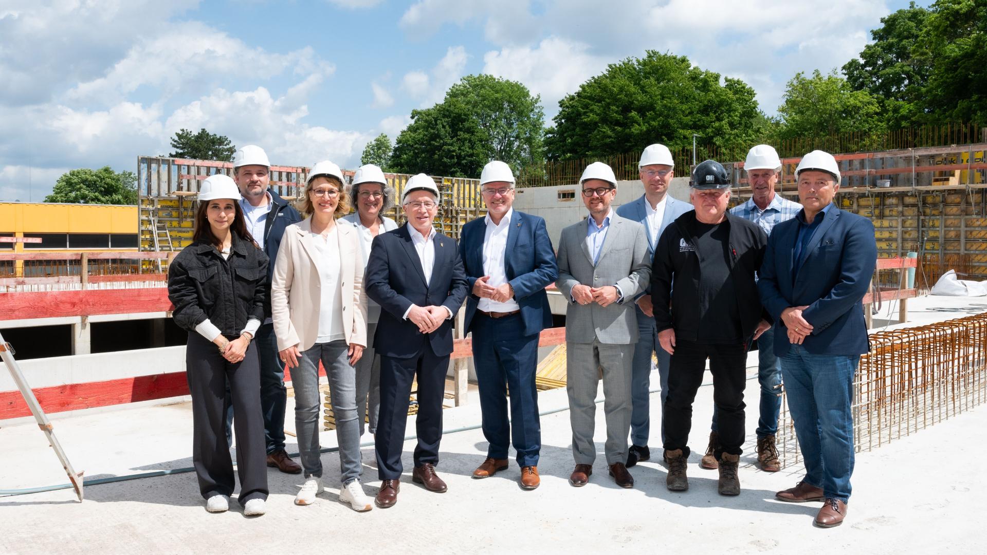 Gruppe von elf Personen in Business- und Freizeitkleidung steht auf der Baustelle des neuen Schwimmbads Heißen in Mülheim an der Ruhr