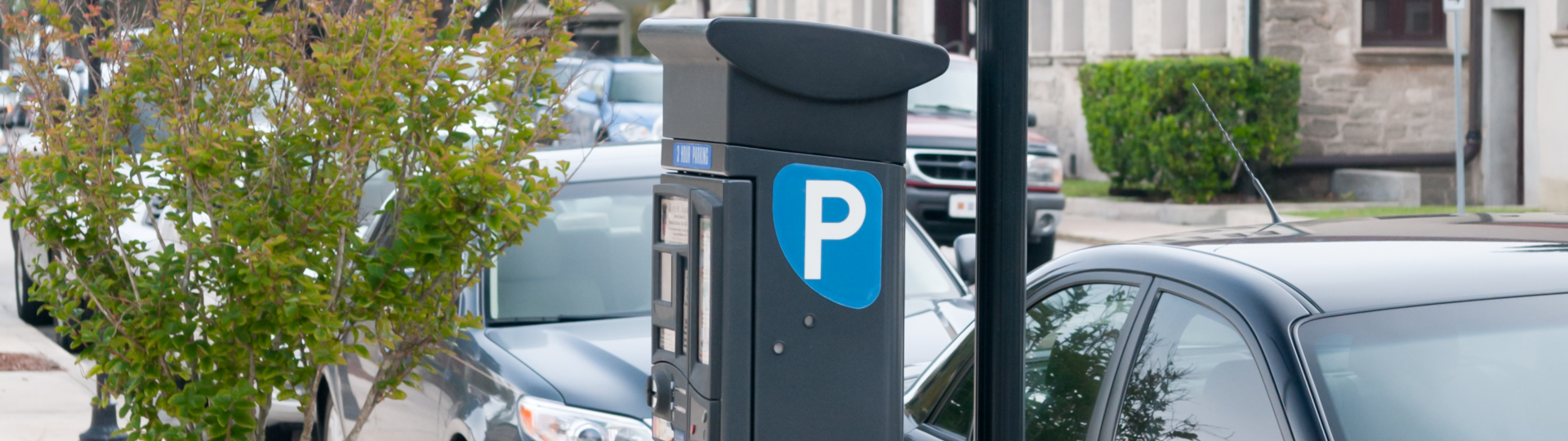 Eine Straße mit zwei parkenden Autos und einem Parkscheinautomaten.