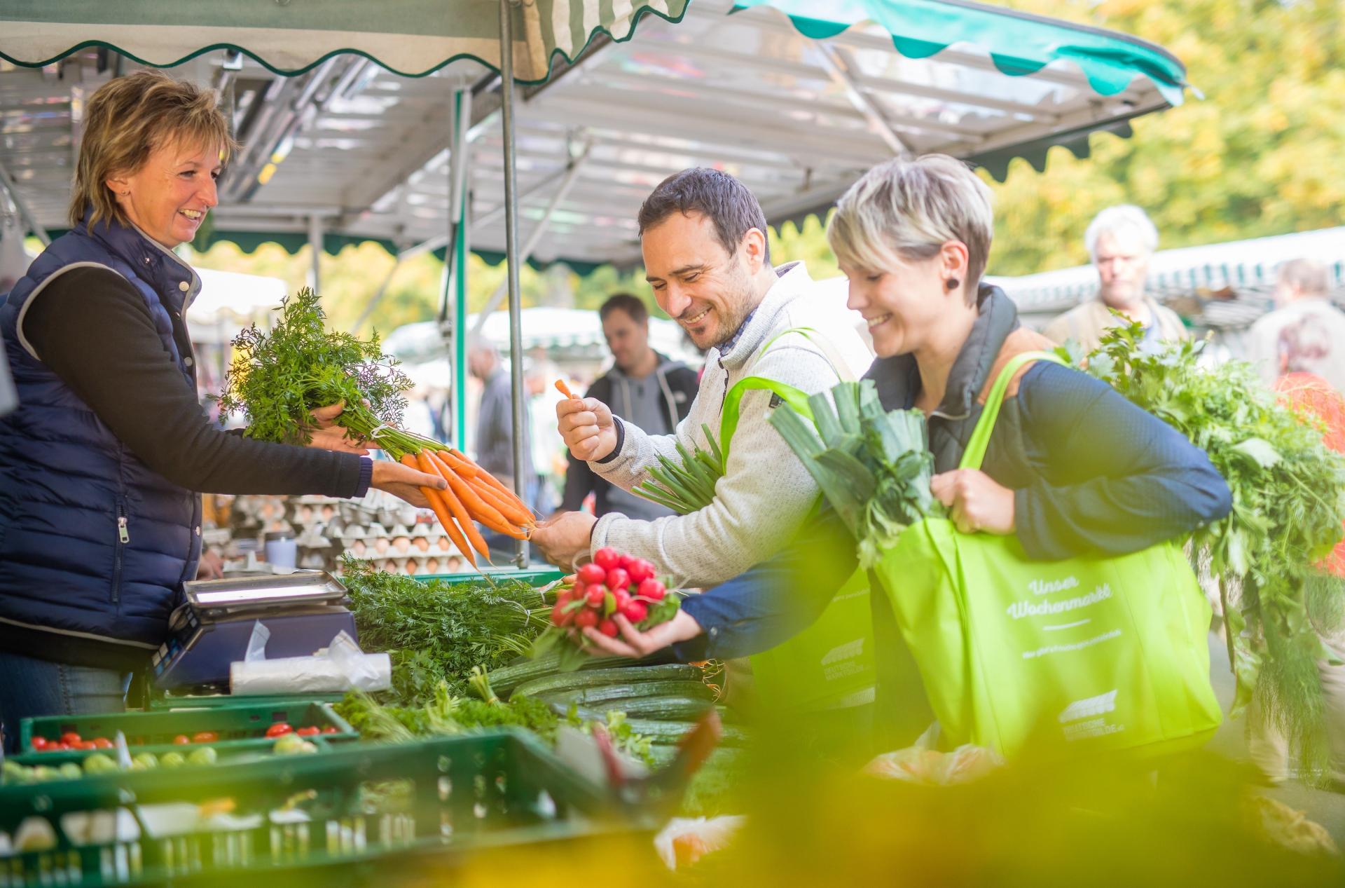 Ein Paar kauft an einem Marktstand Gemüse ein.