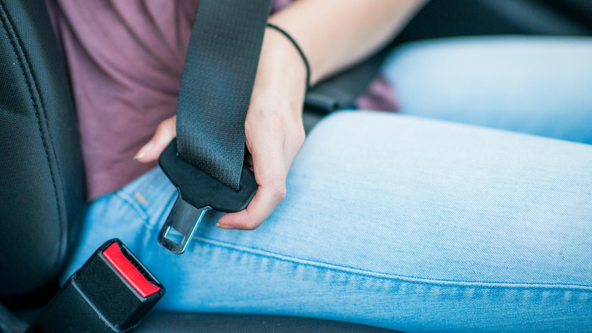 Eine Person im Auto schnallt sich mit dem Anschnallgurt an.