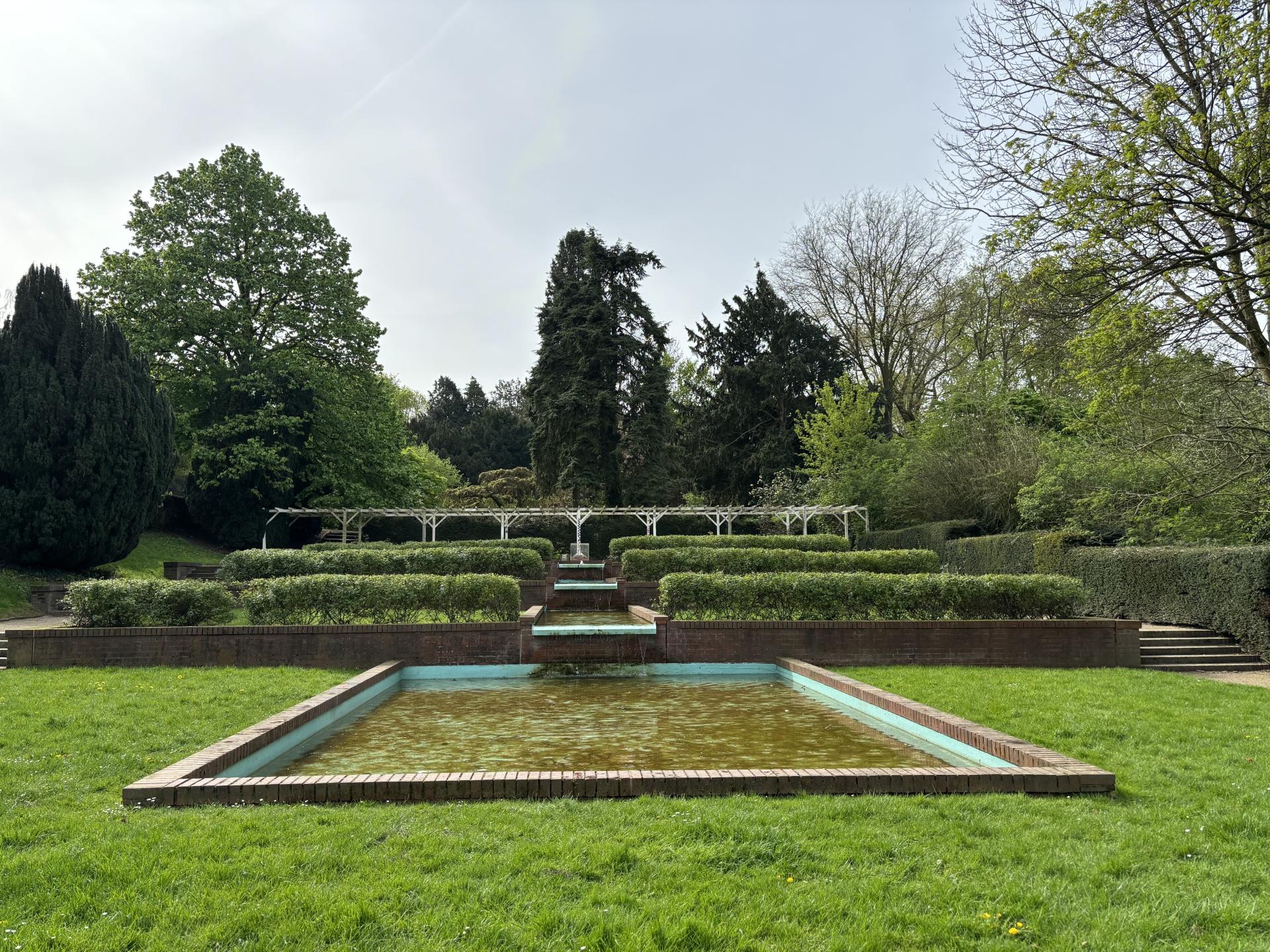 Blick auf die Brunnenanlage und Beete im Rosengarten des Dimbeckparks.