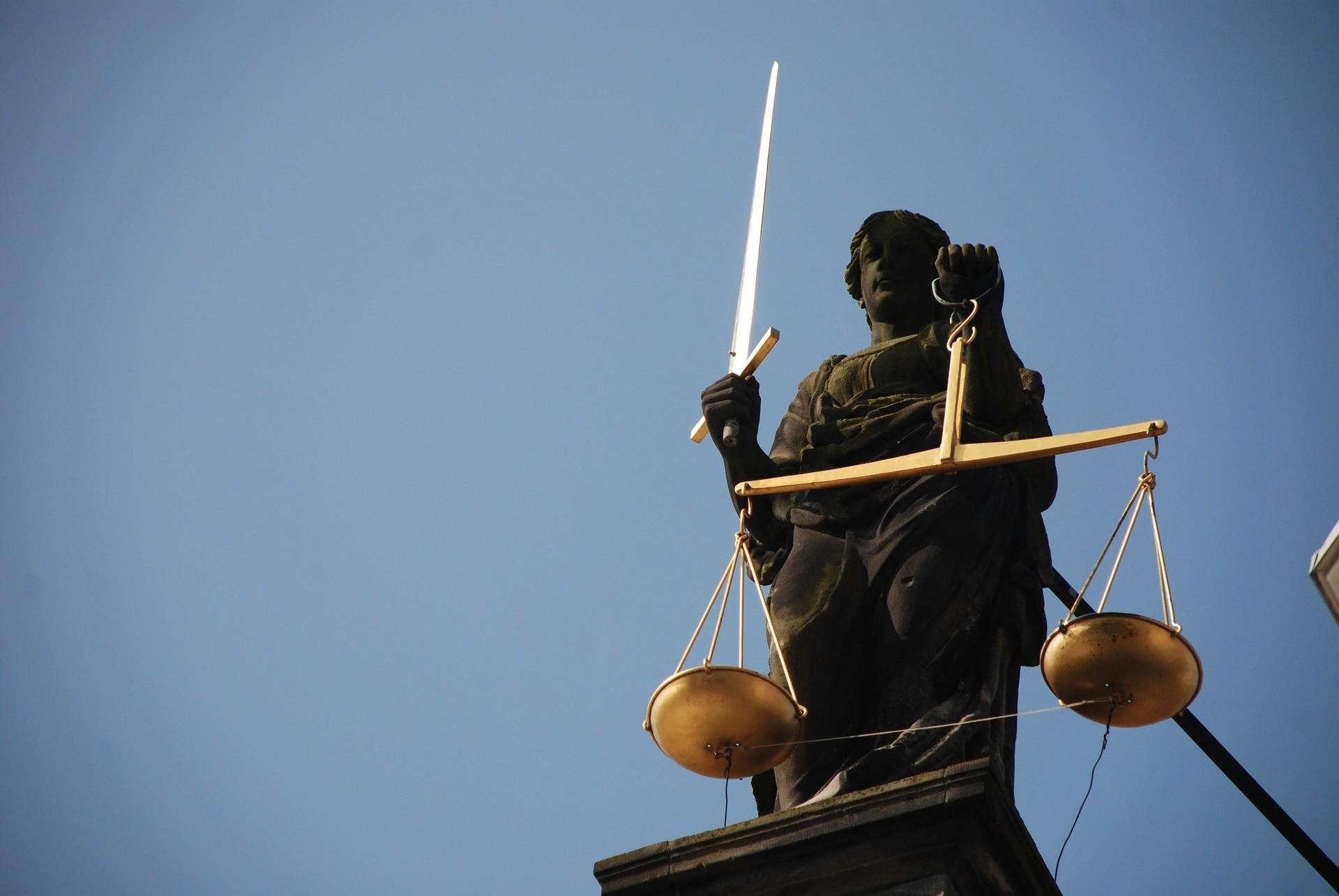 eine Statue, die eine Waage und ein Schwert in der Hand hält