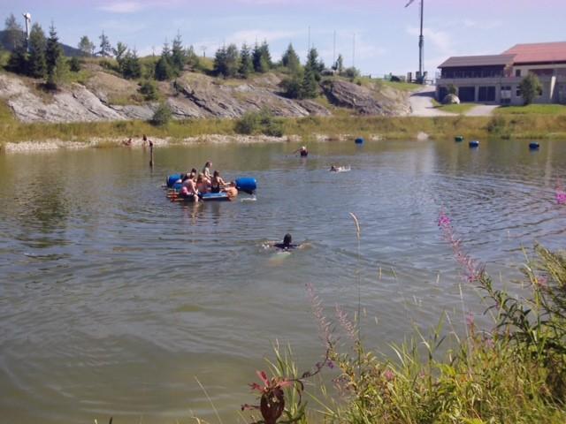 Jugendliche beim Schwimmen und Bootsfahren auf dem kleinen See in der Ferienfreizeit