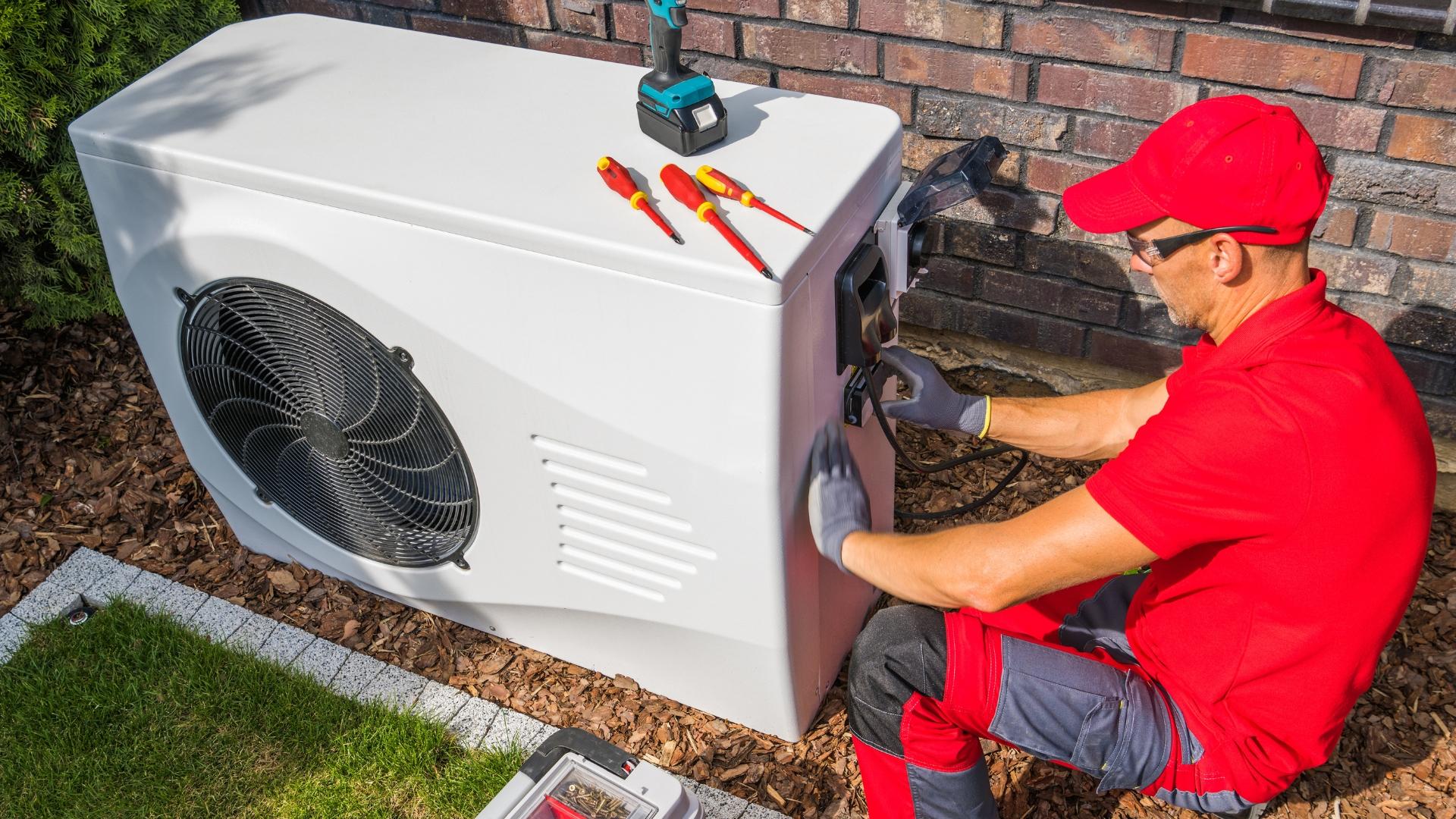 Ein Installateur montiert eine Wärmepumpe.