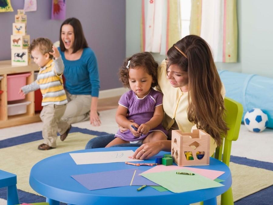 Zwei Kindertagespflegepersonen spielen mit Kleinkindern im Tagespflegenest.