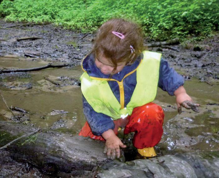 Kleines Mädchen spielt im Matsch, Lernwerkstatt Natur 