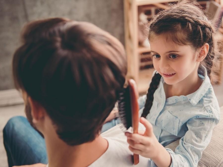 Kita-Kind kämmt die Haare der Tagespflegeperson, Bezugsperson, persönliche Bindung, Tagespflegenest, Kita, Kindergarten, Kinderbetreuung, Pflegevater, Pflegemutter.