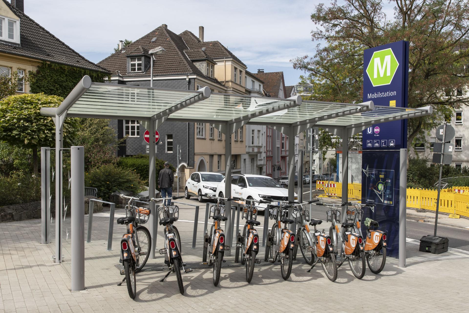 Die Mobilstation an der Von-Bock-Straße mit einem überdachten Fahrradstellplatz mit Leihfarrädern und CarSharing Fahrzeugen im Hintergrund.