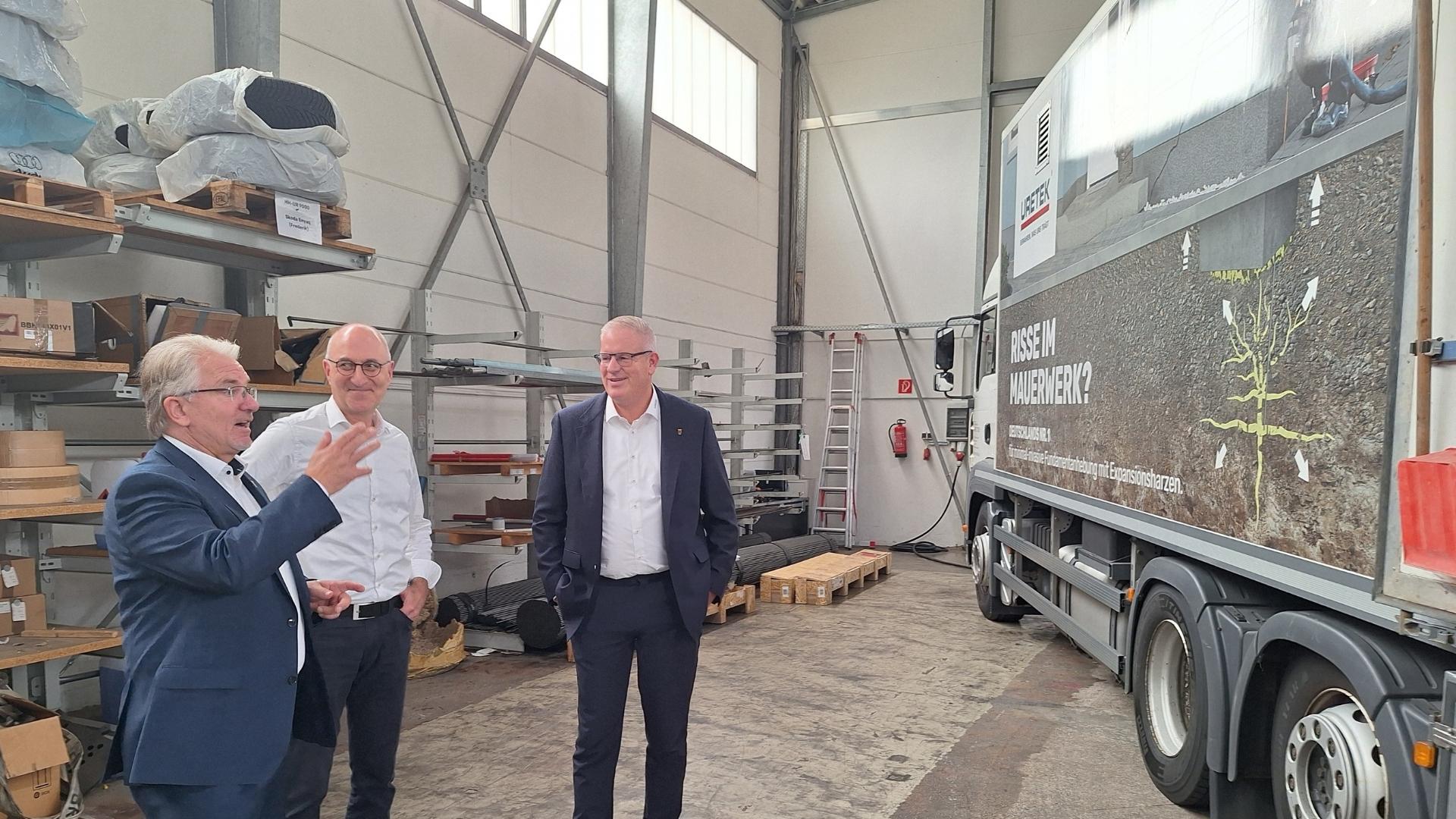 Oberbürgermeister Marc Buchholz (links) steht mit den Geschäftsführern der Firma URETEK Deutschland GmbH vor einem Lkw