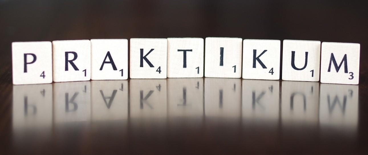 Der Begriff "Praktikum" wird aus 9 Scrabblewürfeln gebildet, die alle einen Buchstaben zeigen.