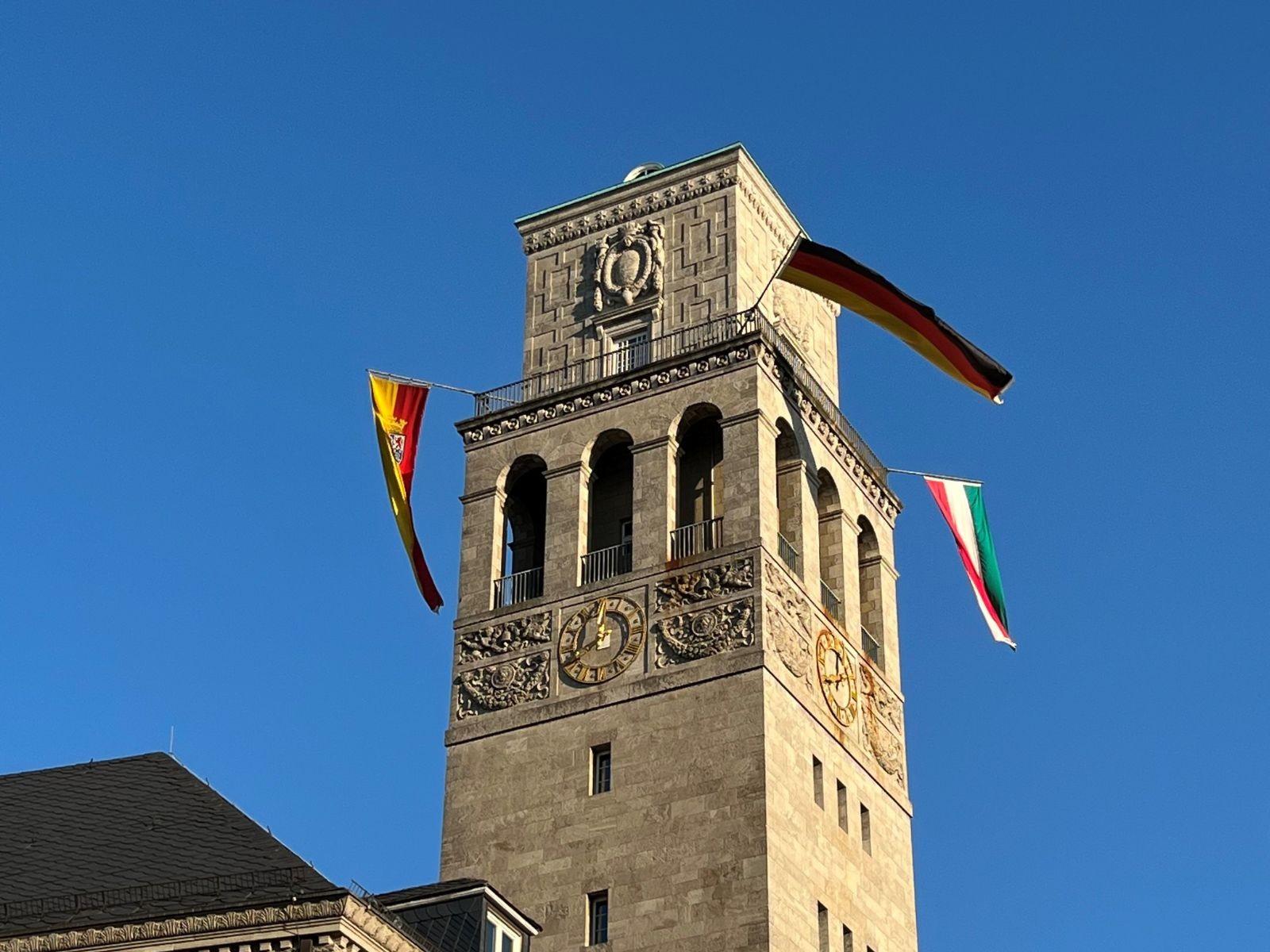 Der Mülheimer Rathausturm ist beflaggt. Die Beflaggung umfasst die Flaggen Europa, Deutschland, Land Nordrhein-Westfalen und Stadt Mülheim an der Ruhr.