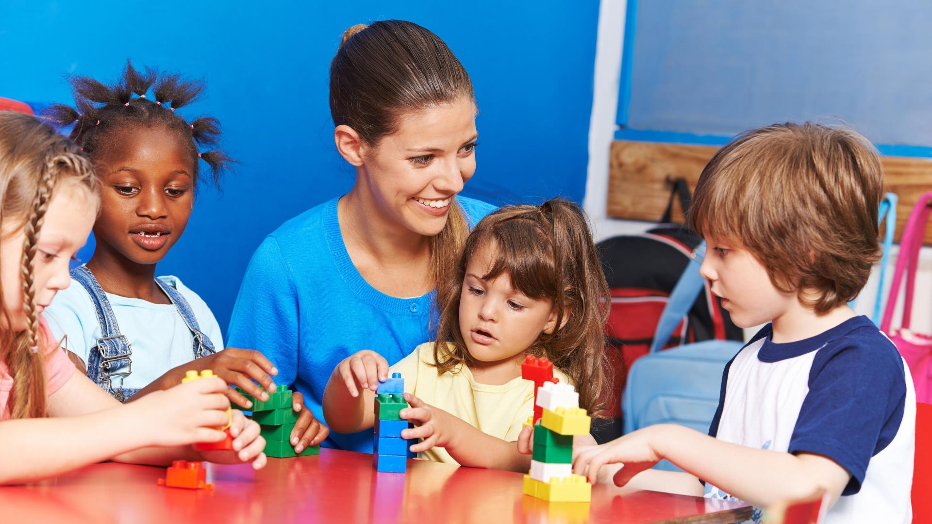 vier Kinder spielen mit einer Erzieherin