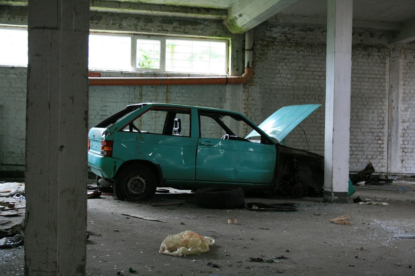Abgemeldetes und in einem Parkhaus abgestelltes, türkises Schrottauto, dass bereits ausgeschlachtet wurde.