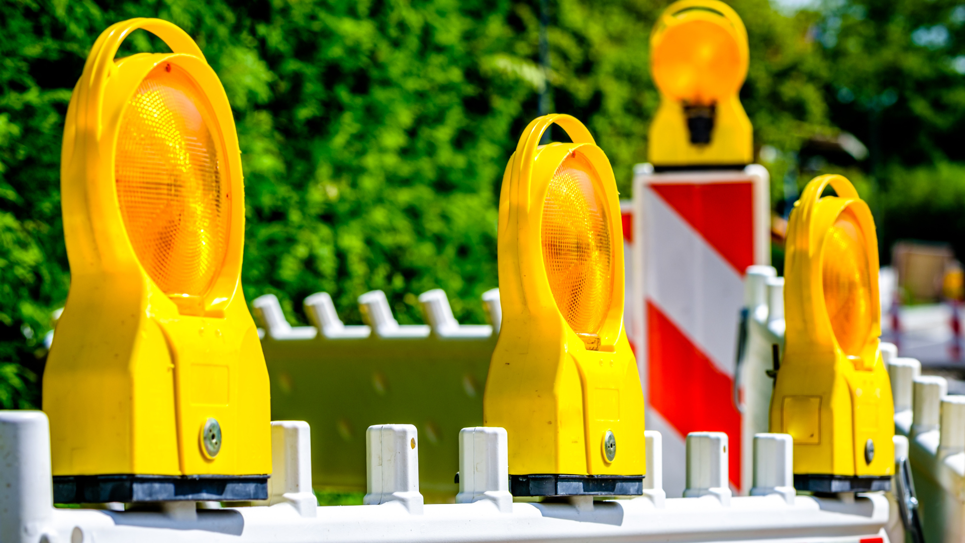 An einer Baustelle sind gelb-orange Warnleuchten auf Warnbaken montiert.