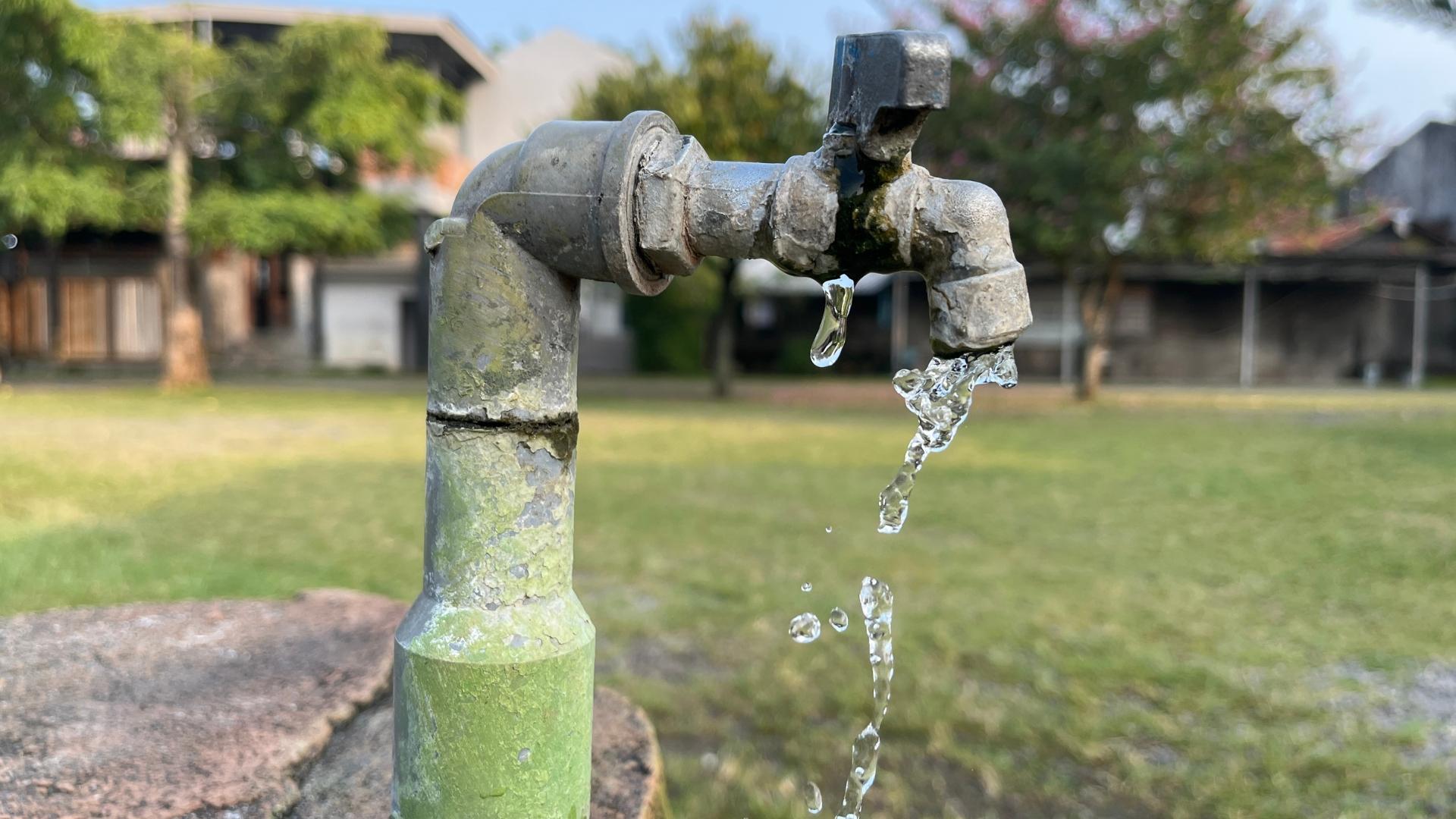 Wasser läuft aus einem Wasserhahn, welcher auf freier Fläche steht.