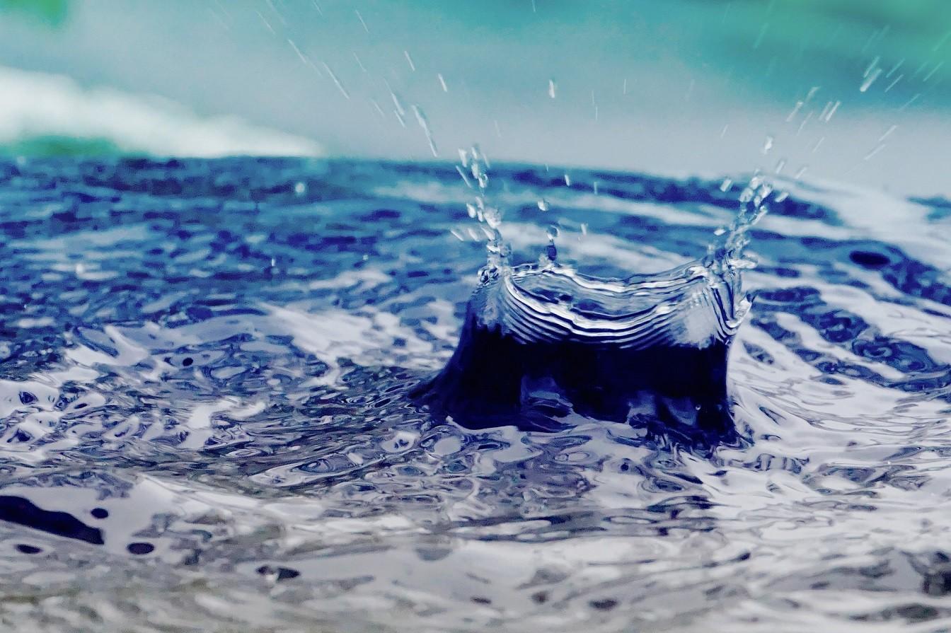 Ein Wassertropfen schlägt auf eine Wasseroberfläche auf.