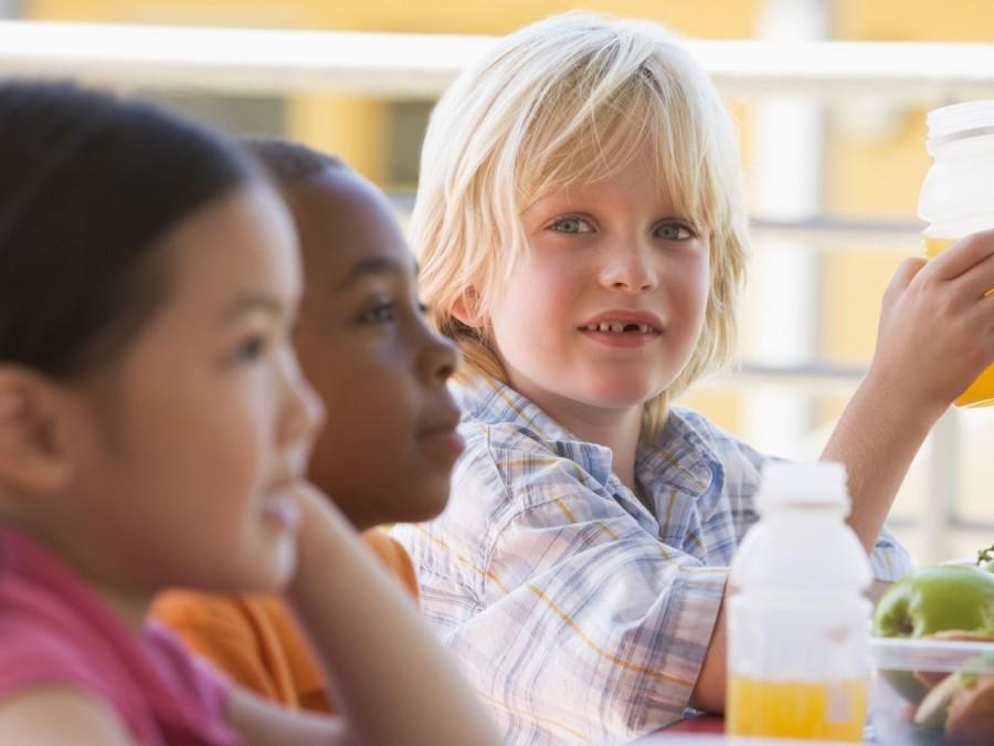 Drei Kinder sitzen gemeinsam am Tisch und essen. Tagespflegenest, Kindergarten, Kinderbetreuung, Pflegevater, Pflegemutter, Kindertagespflege.