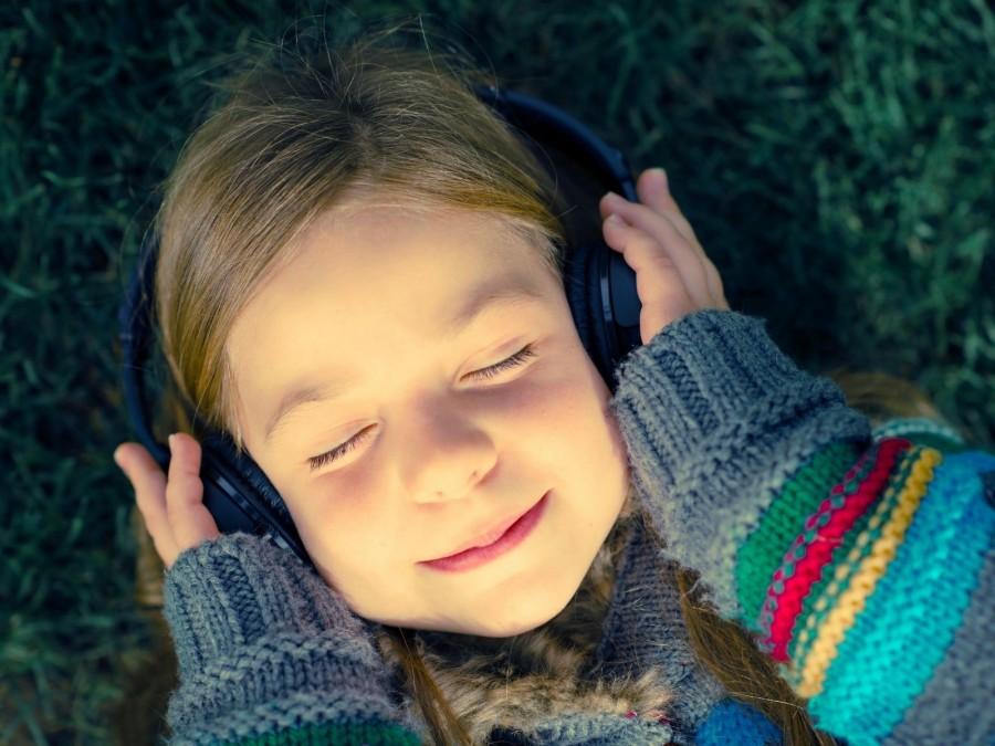 Kleines Mädchen mit Kopfhörern hört Musik zur Entspannung. Tagespflegenest, Kita, Kindergarten, Kinderbetreuung, Pflegevater, Pflegemutter