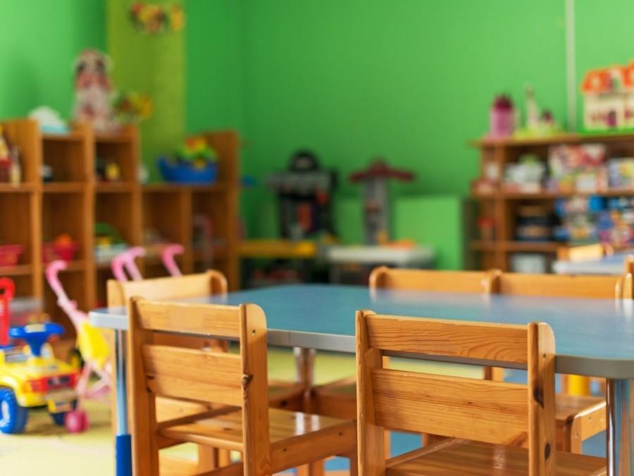 Blick auf einen Kindertisch mit Holzstühlen in einem eingerichteten Kindertagespflege-Raum. Kita, Kinderbetreuung, Prüfung der Eignung von Bewerberinnen und Bewerbern für die Tätigkeit als Tagesmutter oder Tagesvater