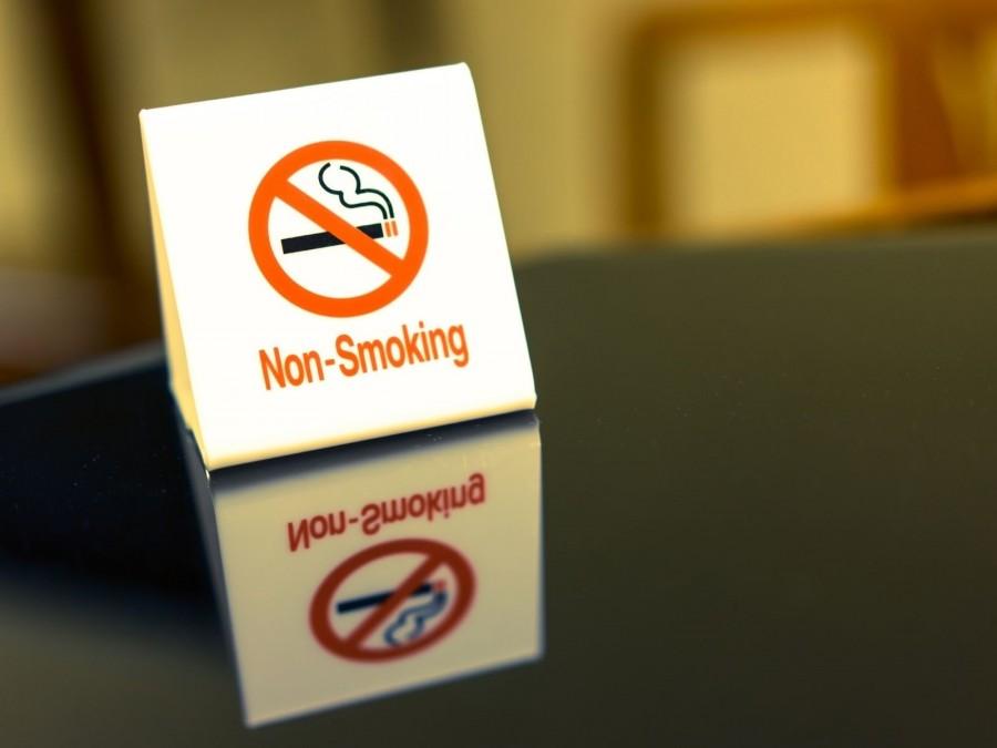 Schild mit durchgestrichener Zigarette und Non-Smoking auf einem Tisch. Rauchen nicht erlaubt, Rauchverbot