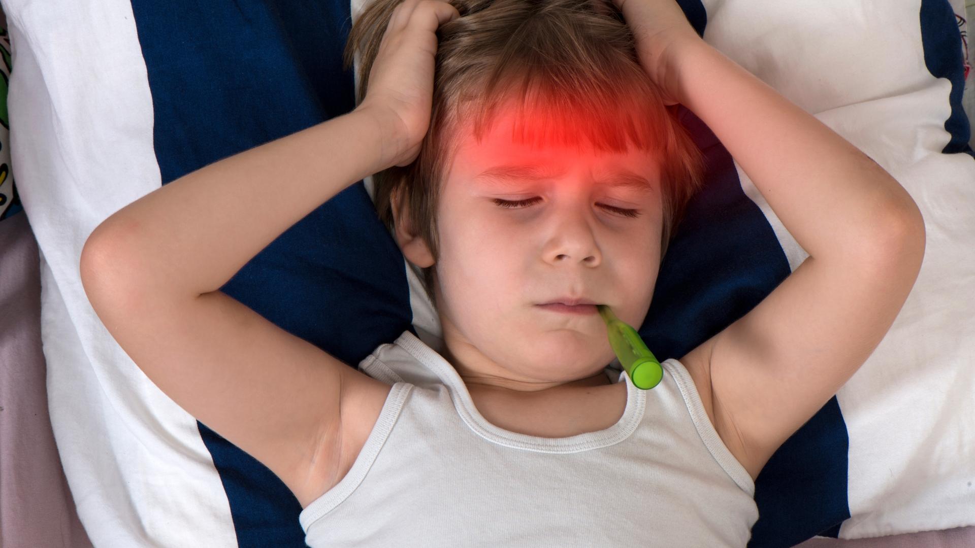 Kind liegt mit Theromemter krank im Bett