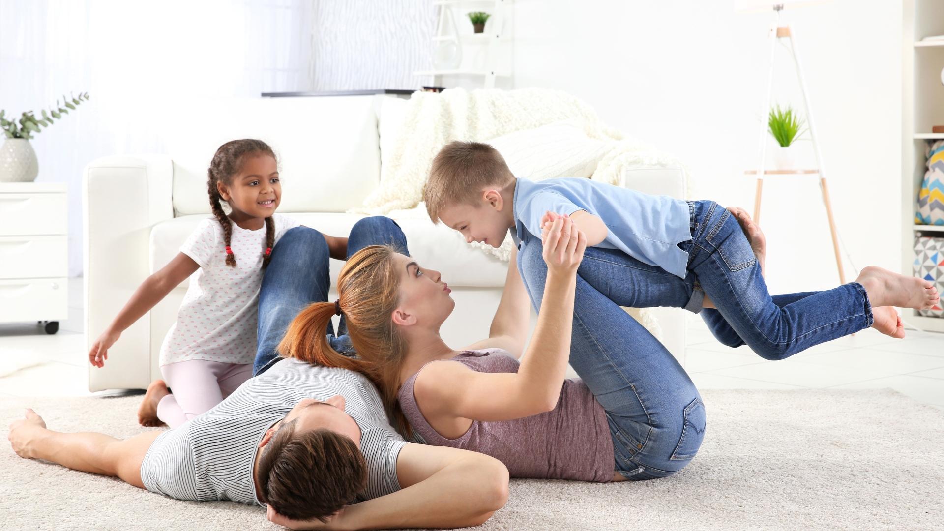 eine vierköpfige- Familie die auf dem Teppich tobt