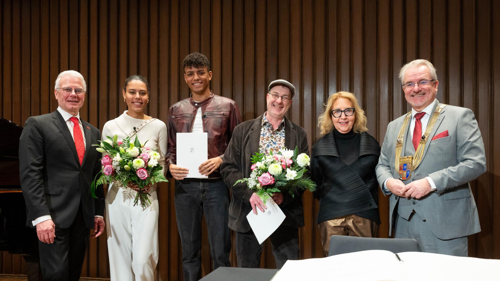 Sechs Personen stehen nebeneinander vor einer Holzpaneelwand, im Kammermusiksaal der Stadthalle Mülheim an der Ruhr.