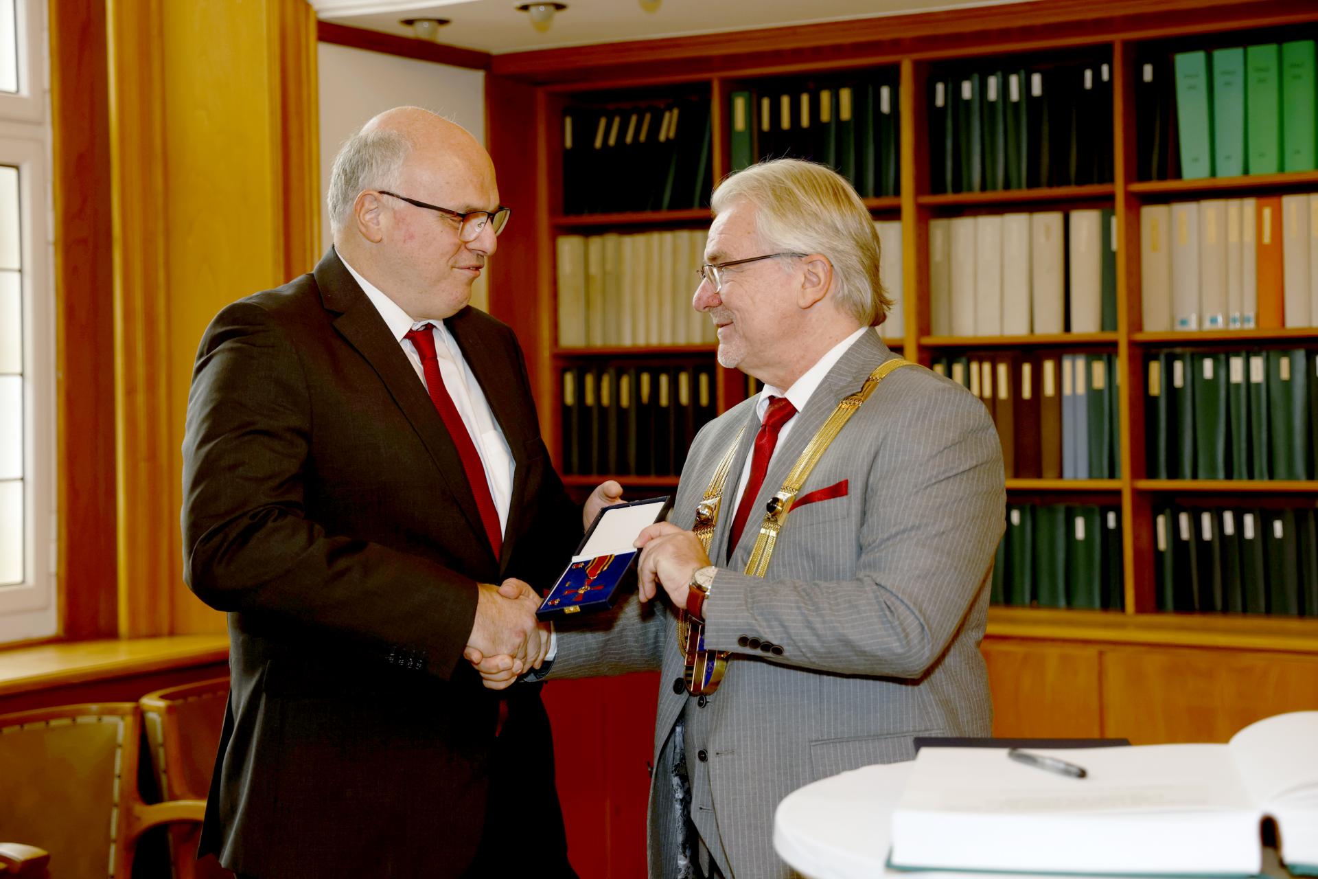 In der Rathausbibliothek überreicht Oberbürgermeister Marc Buchholz das Verdienstkreuz an Claus Kampermann.