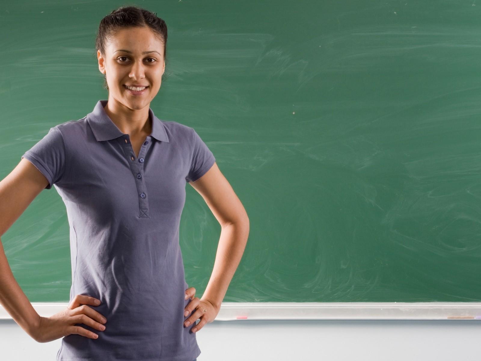 Das Foto zeigt eine junge Lehrerin vor einer Schultafel