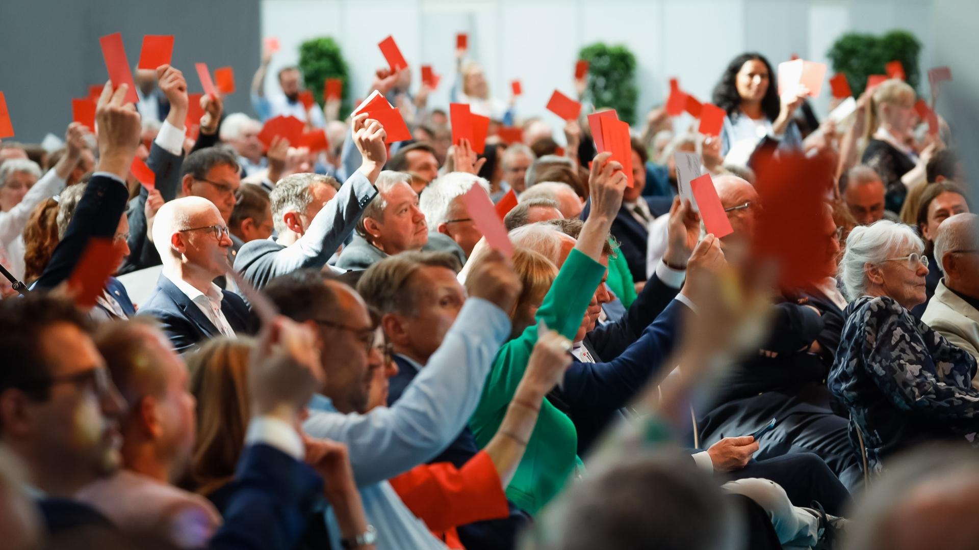 Menschenmenge stimmt ab und hält dafür eine rote Karte in die Höhe