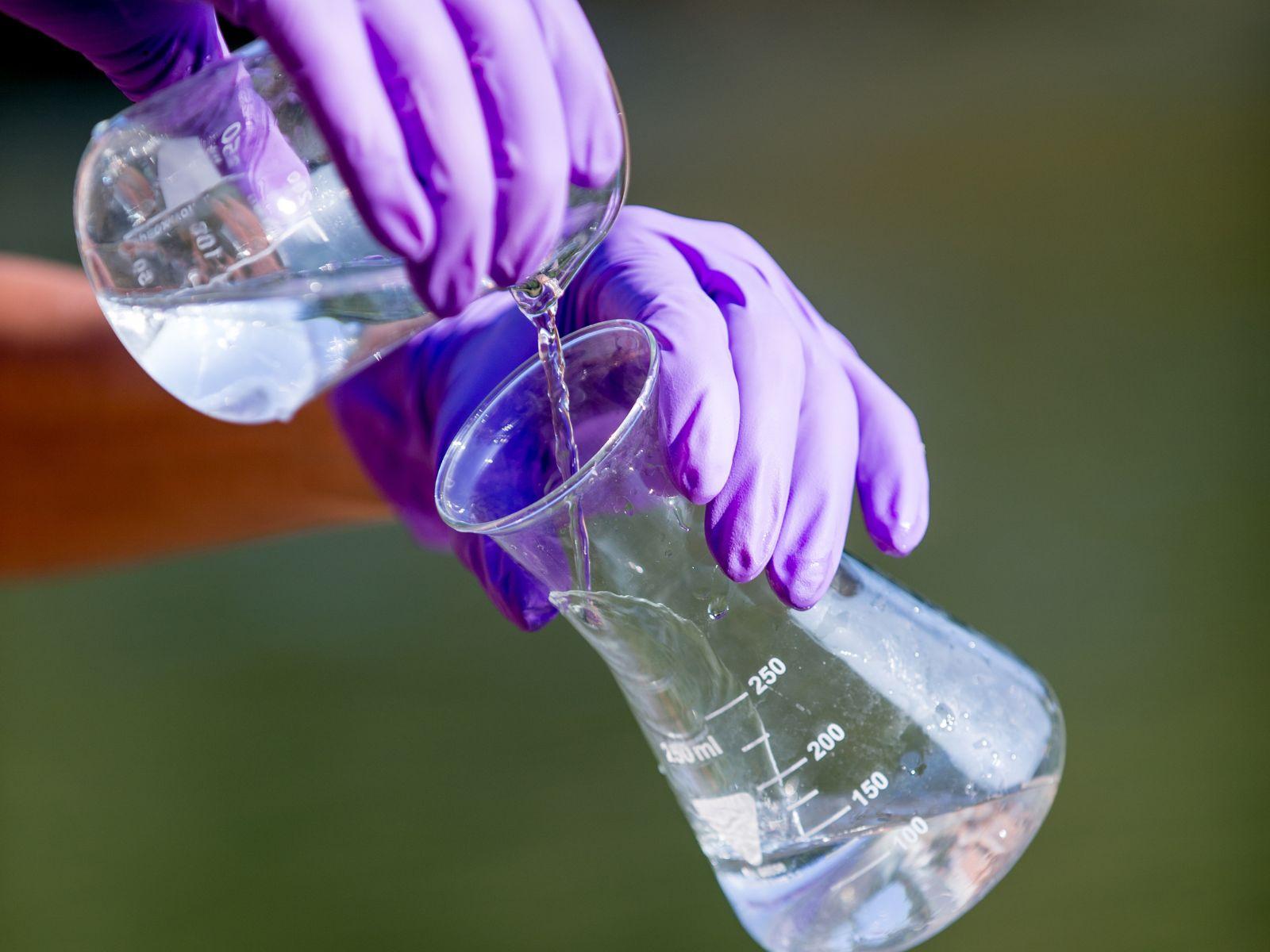 Eine Person hält eine Wasserprobe in den Händen.