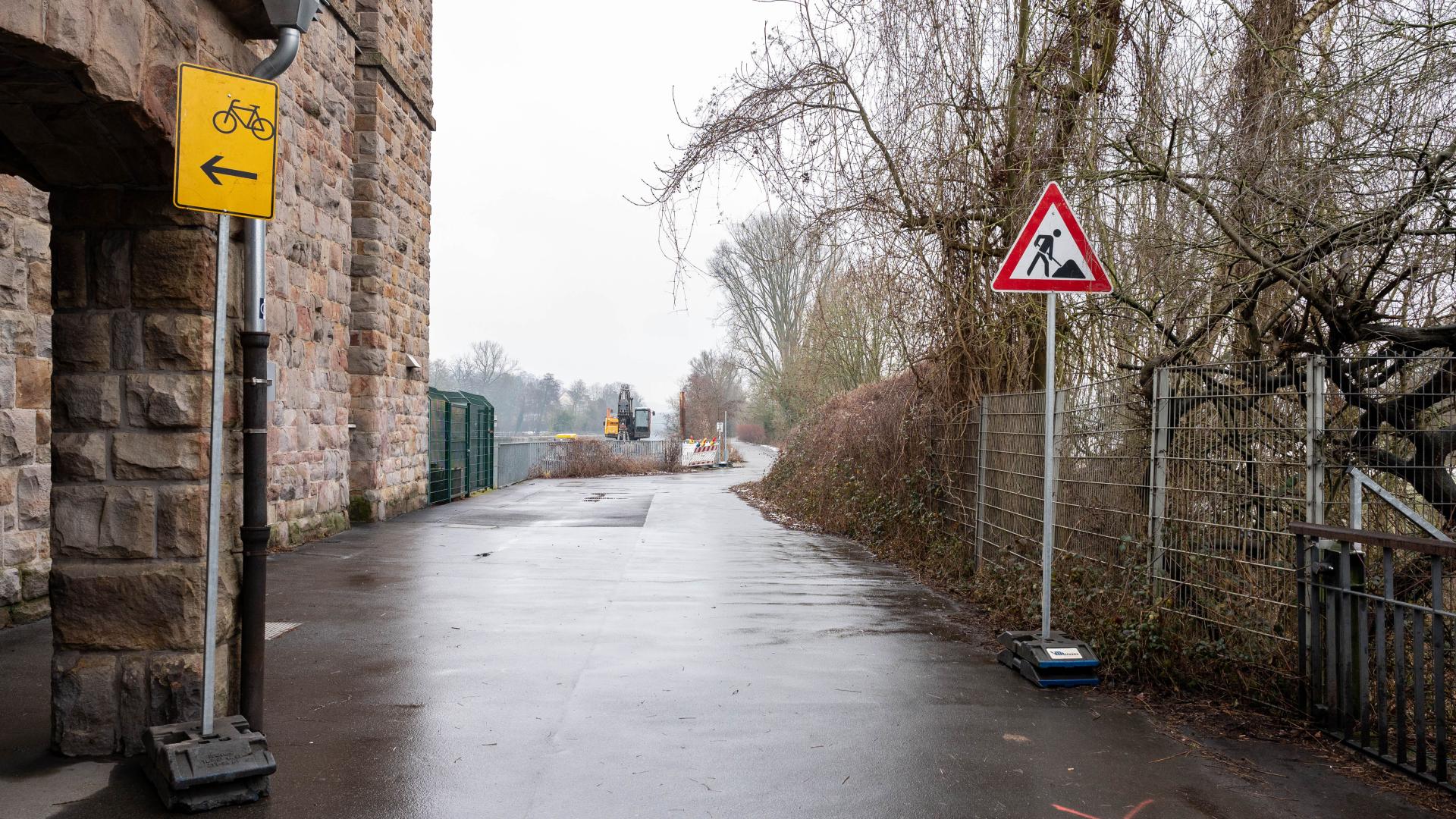 Sperrung des Ruhrinselwegs mit Baustellenschild und gelbem Fahrradwegweiser nach links. Fahrradweg an der Ruhr
