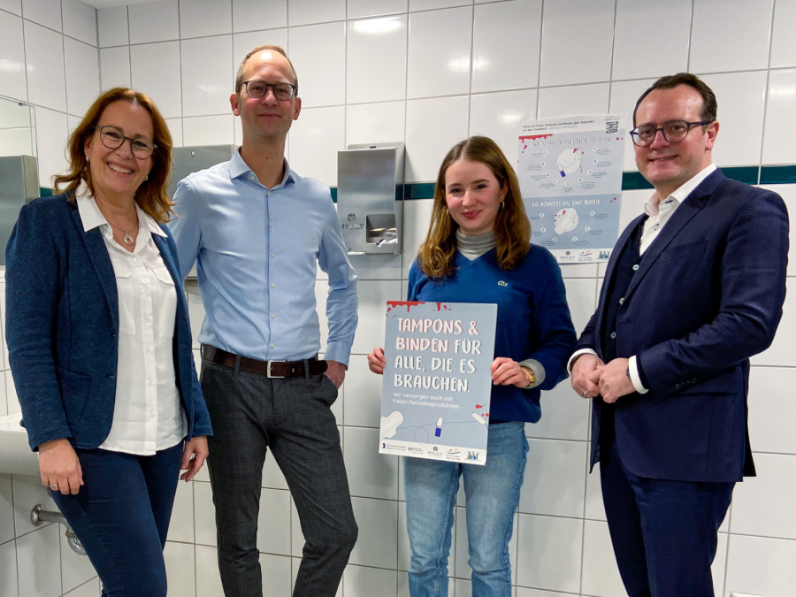Die Personen stellen den Spender mit den Periodenprodukten am Gymnasium Heißen vor.