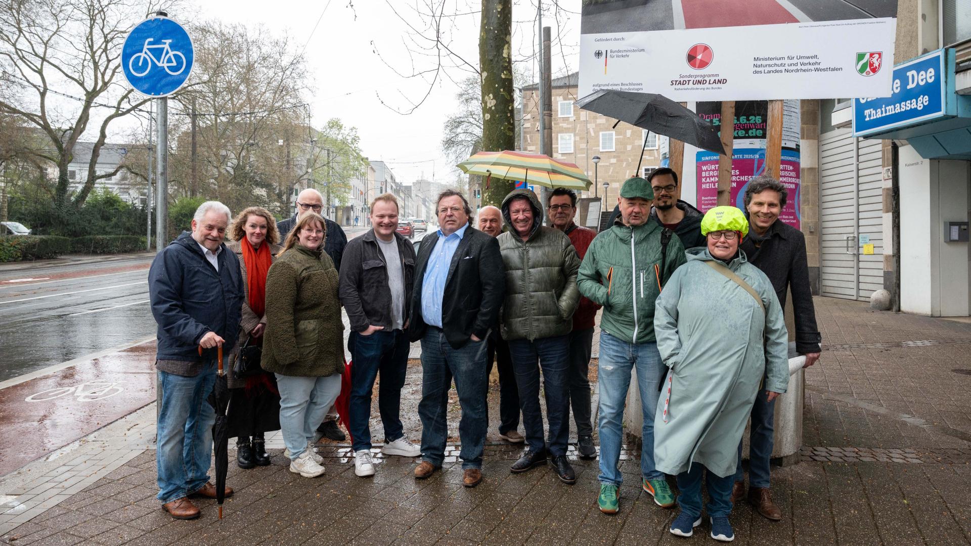Gruppe von Menschen steht auf einem Bürgersteig neben dem fertigen Radweg an der Kaiserstraße