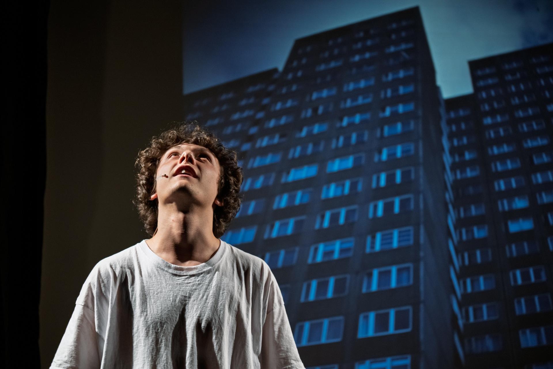 Szene aus dem Stück "Heute Nacht um 03.45 Uhr" mit einem Schauspieler vor einer Häuserkulisse auf der Bühne